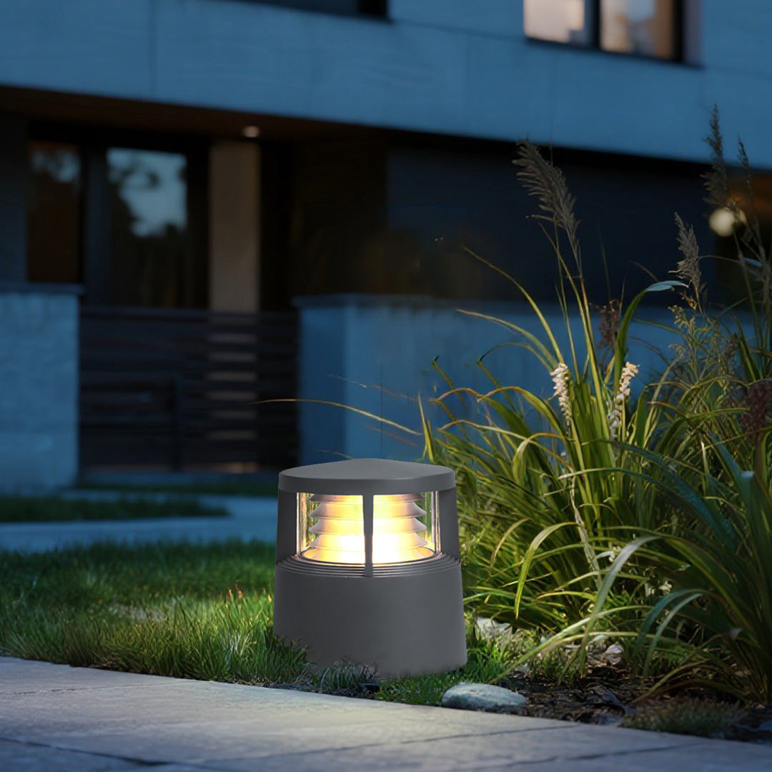Outdoor bollard light in front yard casting soft illumination at dusk