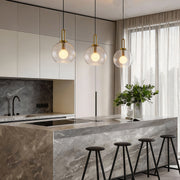 Frosted glass mini pendant lights illuminating a modern kitchen island with warm, diffused glow.
