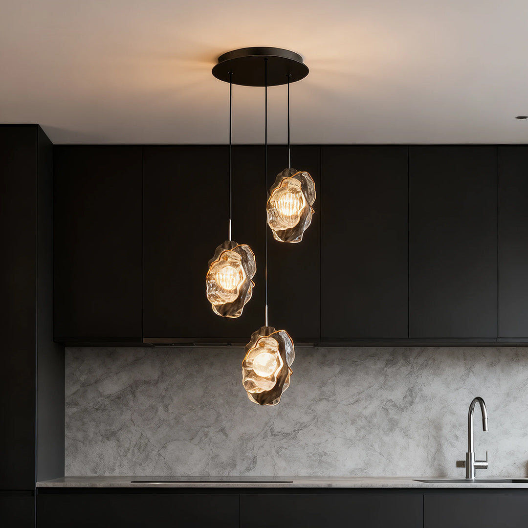 Cluster of fun pendant lights glowing warmly above contemporary kitchen island with grey walls