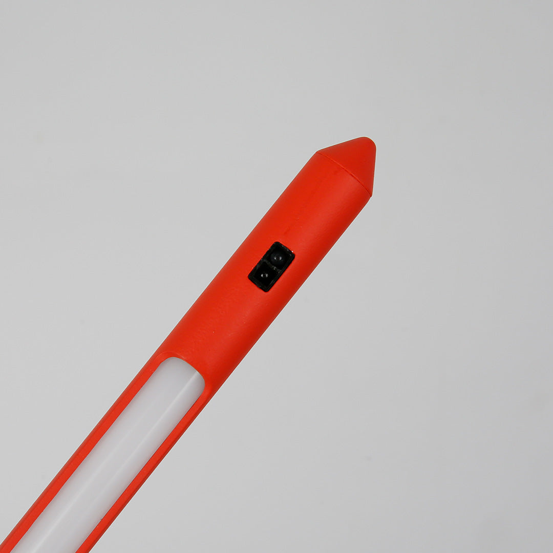 Functional three legged table lamp with red accent providing directional lighting for detailed work