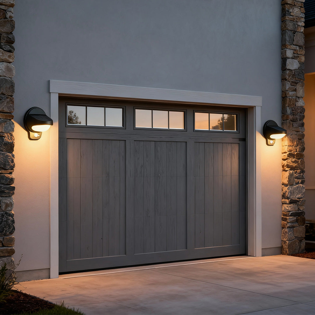 Vintage outdoor wall lights flanking a large garage door with warm illumination.