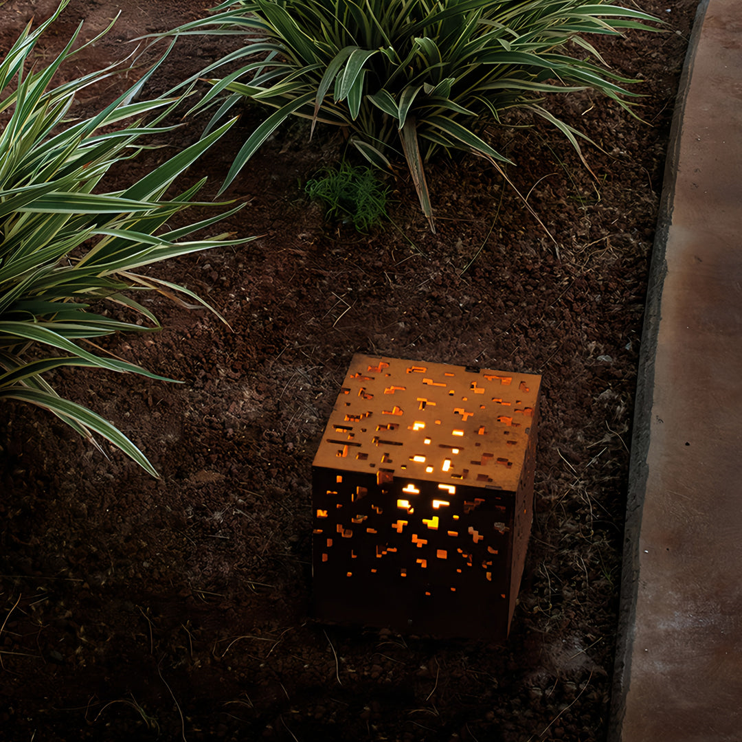 Cube-shaped black outdoor lantern lights set among greenery, creating warm accent lighting in the garden.