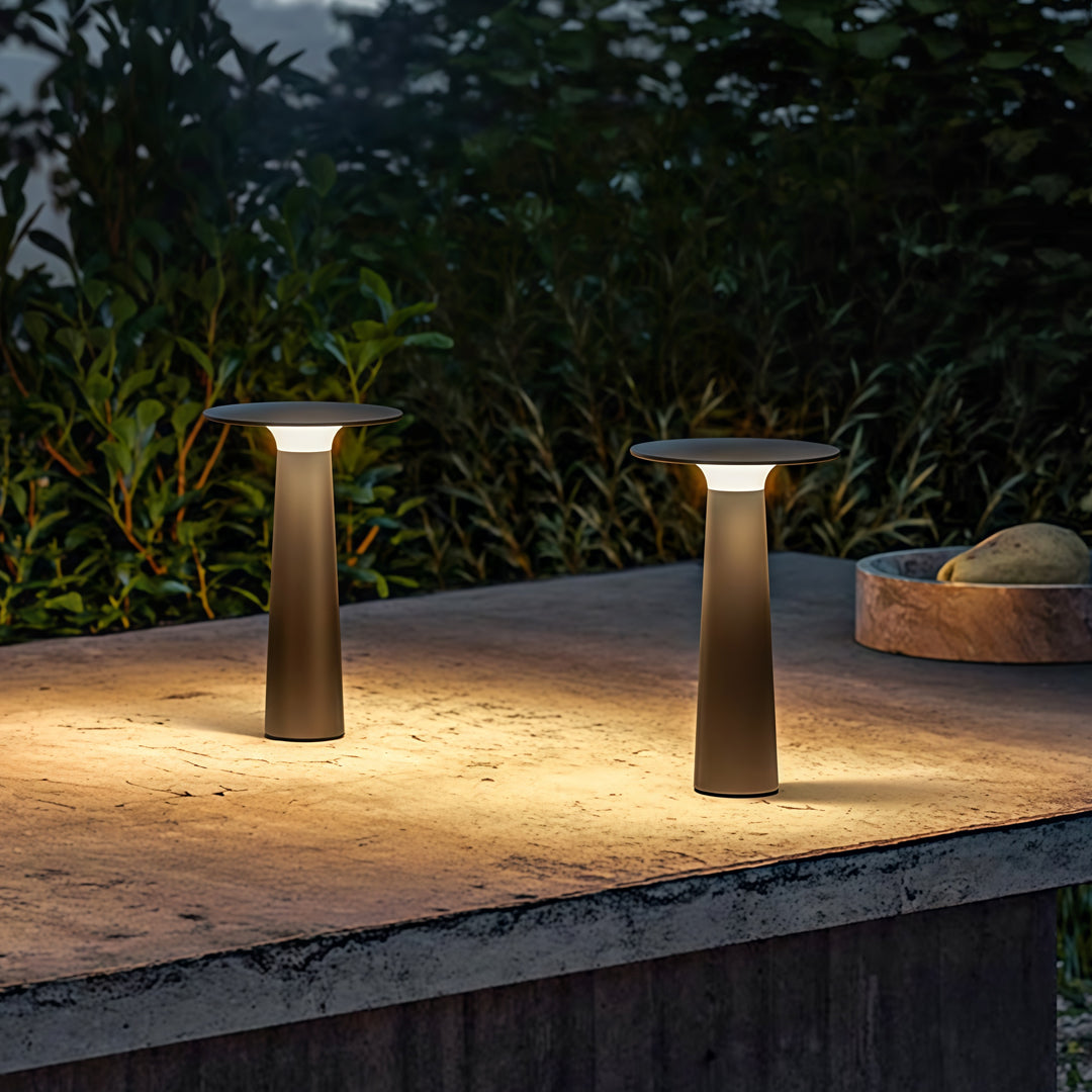 Outdoor led table lamp lighting a garden seating area with warm ambient light.
