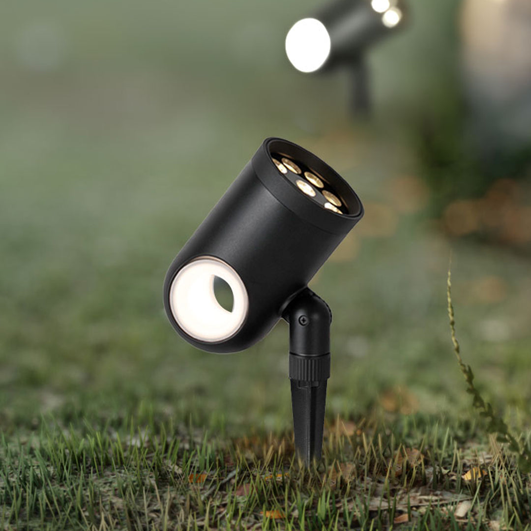 Small waterproof spotlight positioned in a garden bed for focused outdoor lighting.