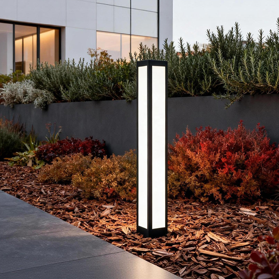 Modern garden bollard light installed along a pathway, providing elegant illumination for outdoor landscapes and gardens.