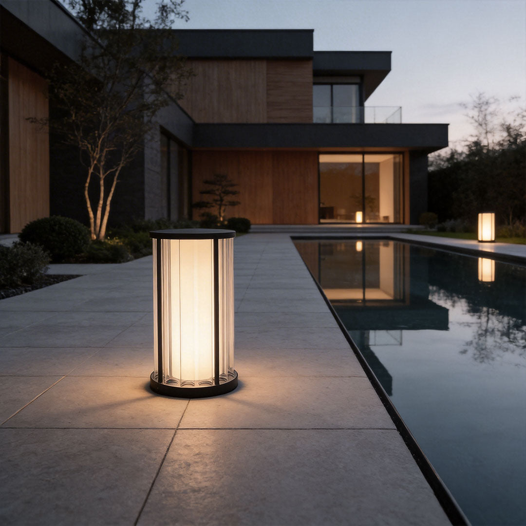 Garden bollard lighting with a modern design, lighting up a poolside walkway.