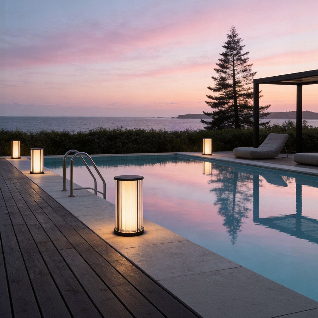Garden bollard lighting with a sleek design, providing warm illumination near a pool at sunset.