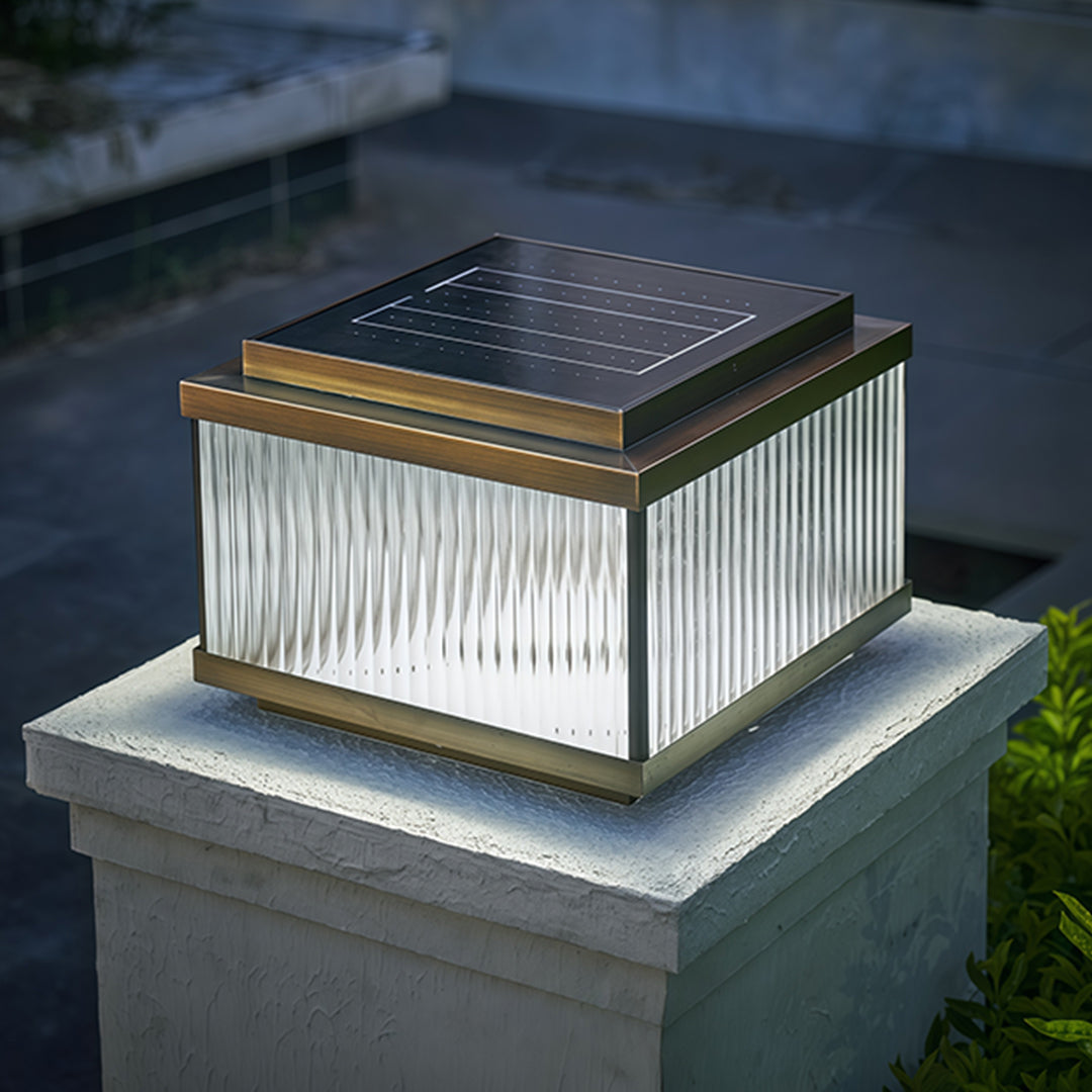 Copper pillar lights with amber glow positioned on weathered stone pillar in garden setting