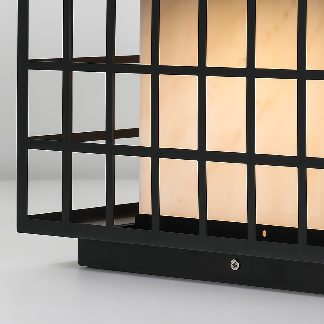 Modern gate pillar light with a black finish, installed on a stone pillar near a garden entrance.