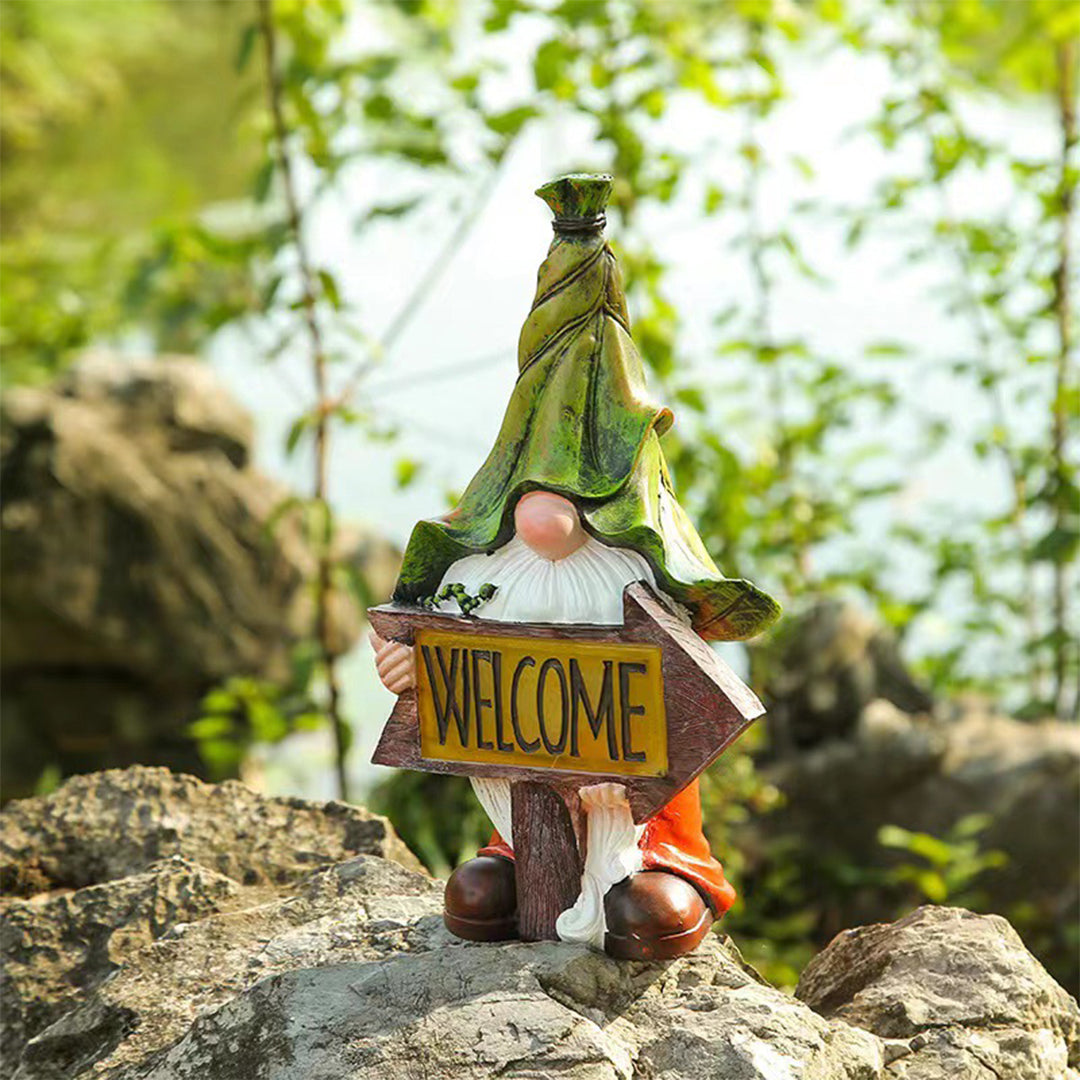 Garden gnome with welcome sign positioned among rocks creating charming landscape accent