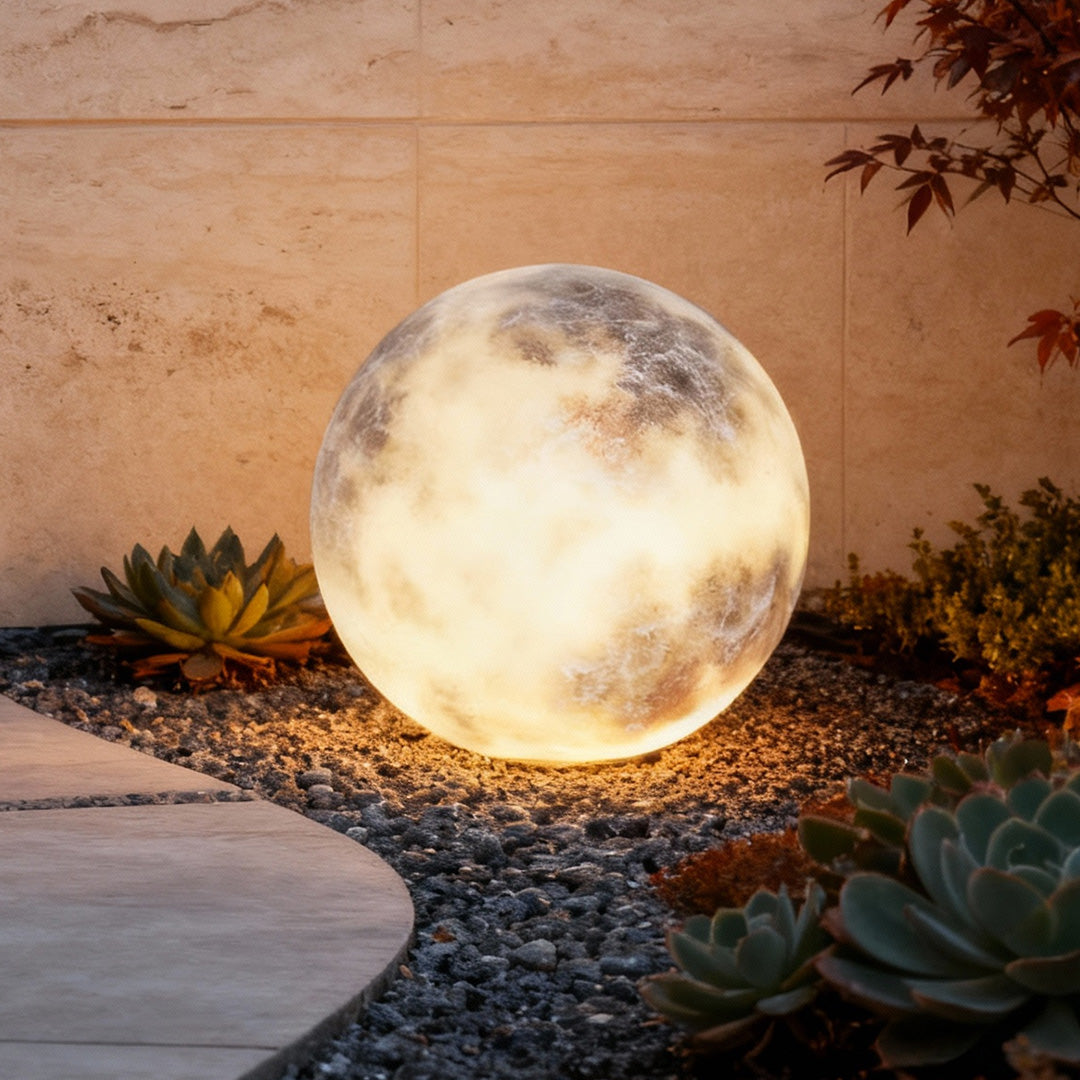 Moon light sphere placed in a garden landscape at night.