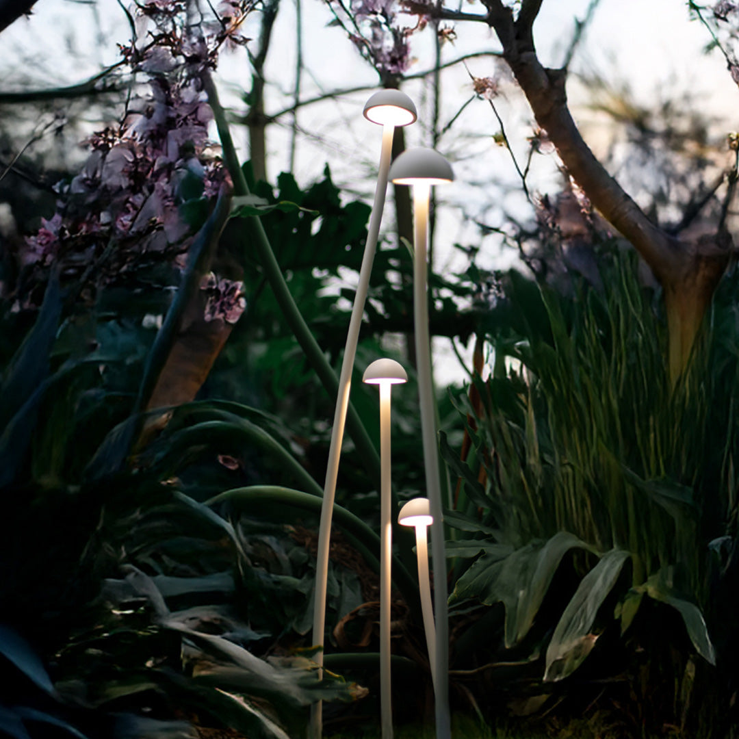Natural outdoor garden setting with modern white mushroom-style lights for landscaping among plants