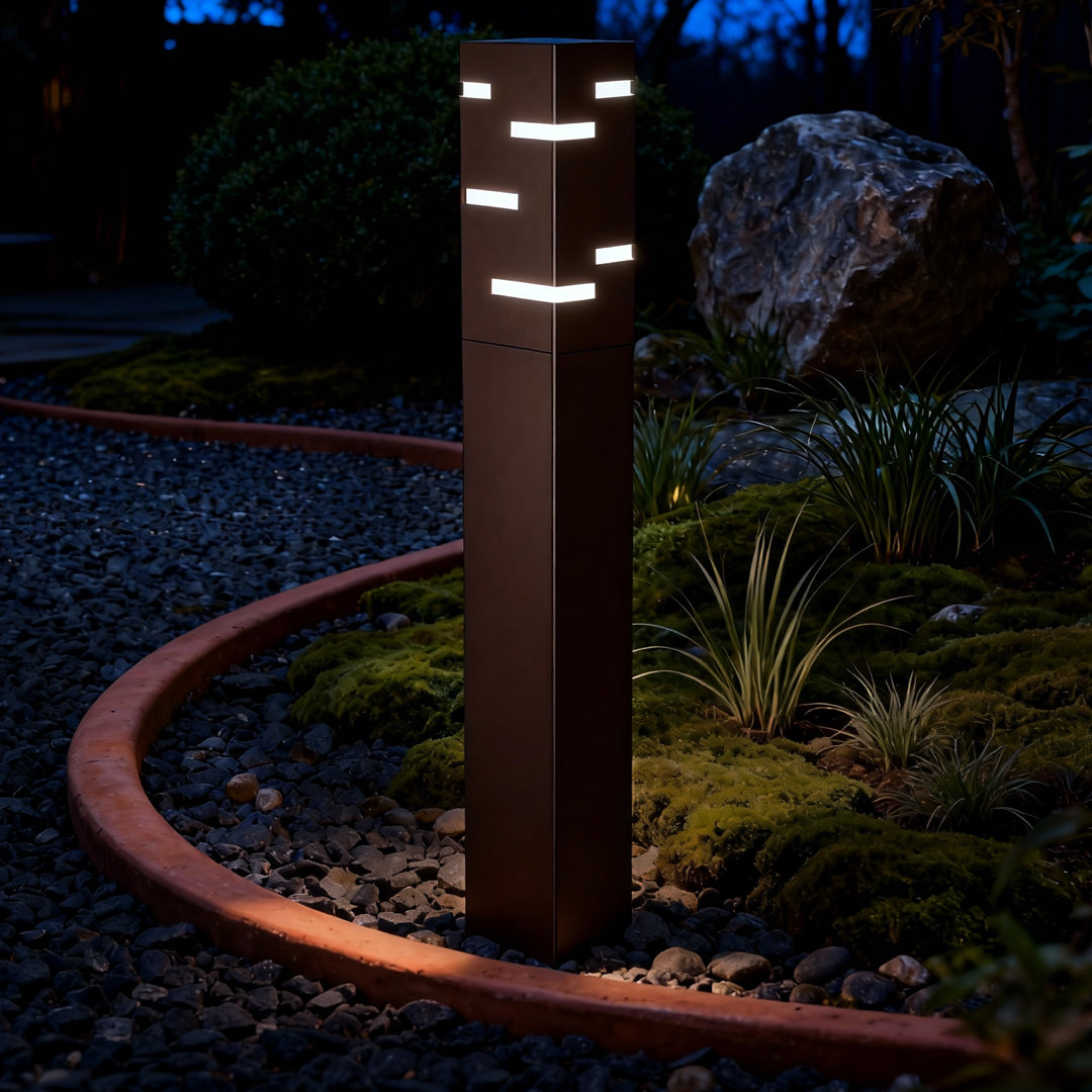 Black led bollard lights glowing warmly along a garden path, providing stylish layered lighting for nighttime outdoor spaces.