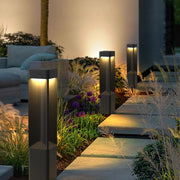Warm outdoor pathway illuminated by modern bollards lighting fixtures placed along garden edges.