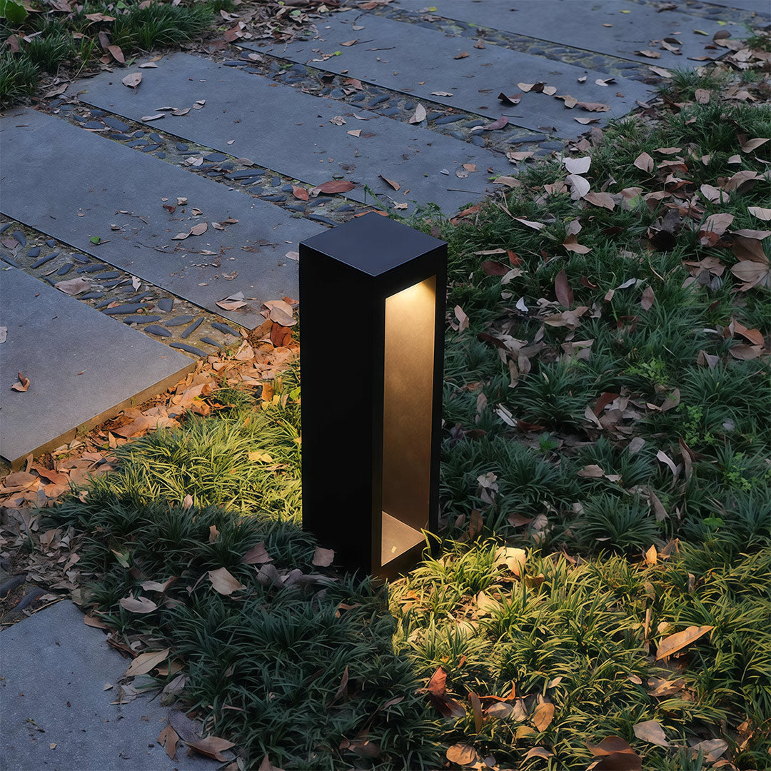 Garden pathway light installed along a paved pathway, providing warm and inviting illumination.