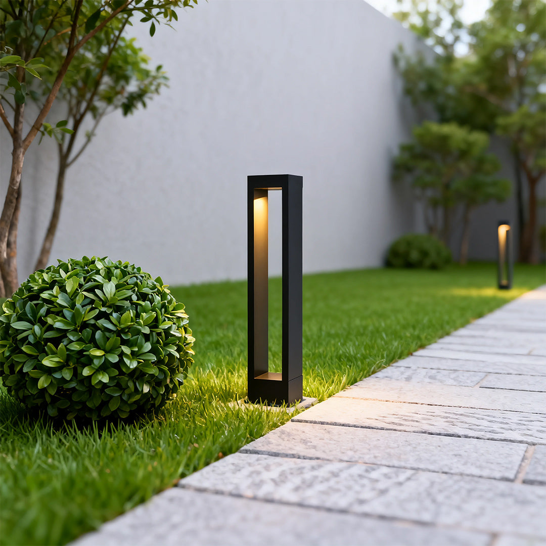 Garden pathway light near a garden with shrubs, adding a contemporary touch to the outdoor space.