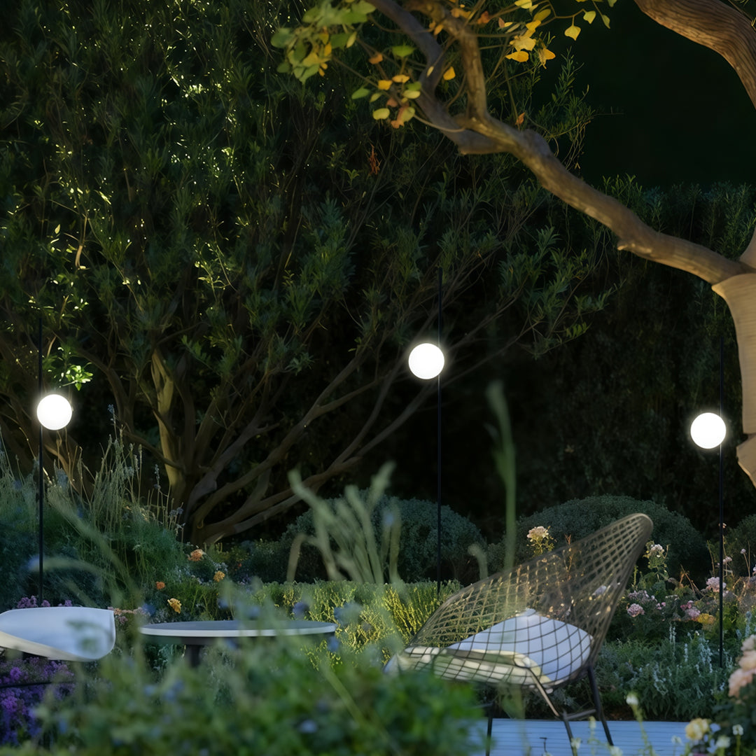 Multiple white glowing garden post lights placed among plants, offering decorative and functional garden pathway lighting in landscaped foliage.
