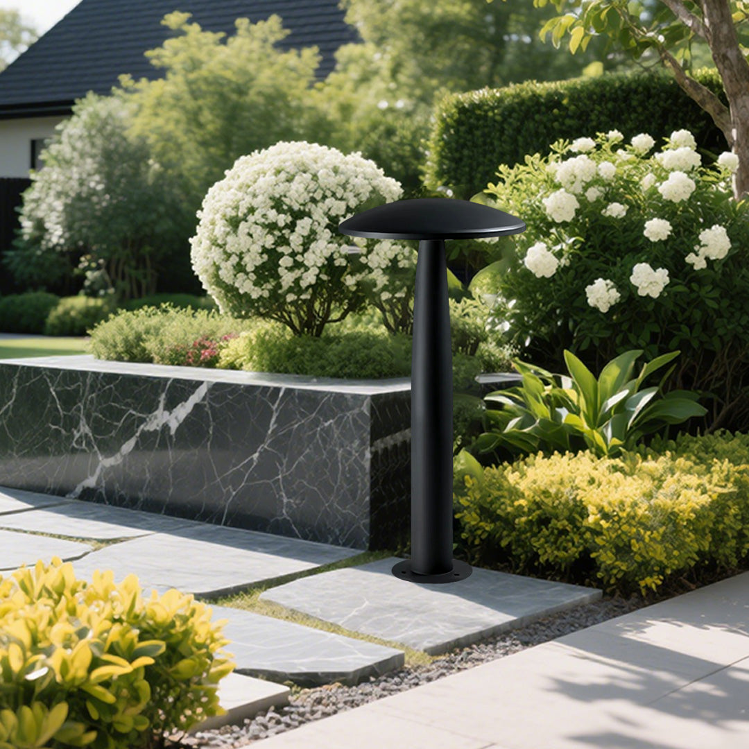 Modern black mushroom bollard light illuminating a garden pathway with lush greenery and decorative plants.