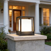 Garden pedestal lights with a modern square lantern design placed on a stone pillar by a front porch.