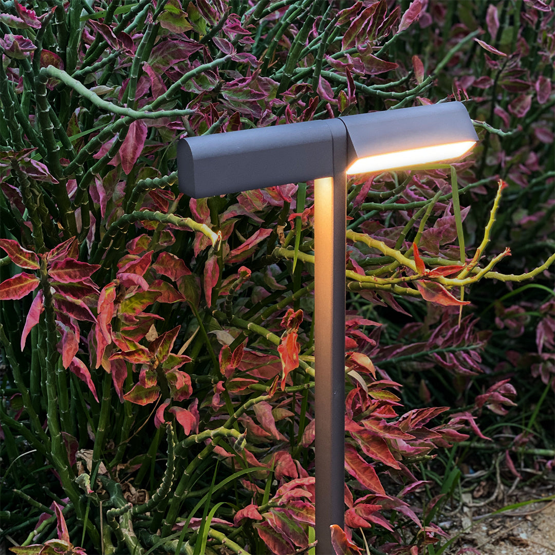 Modern T-head garden lamp casting a soft glow over vibrant shrubs, designed for elegant led pathway lighting.