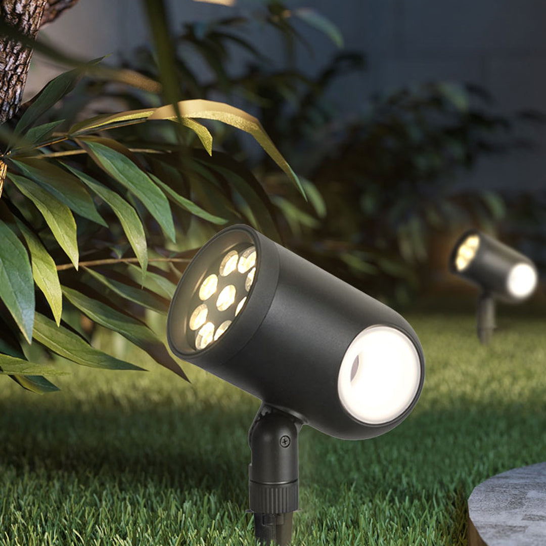Compact waterproof spotlight installed in garden shrubs providing accent lighting.