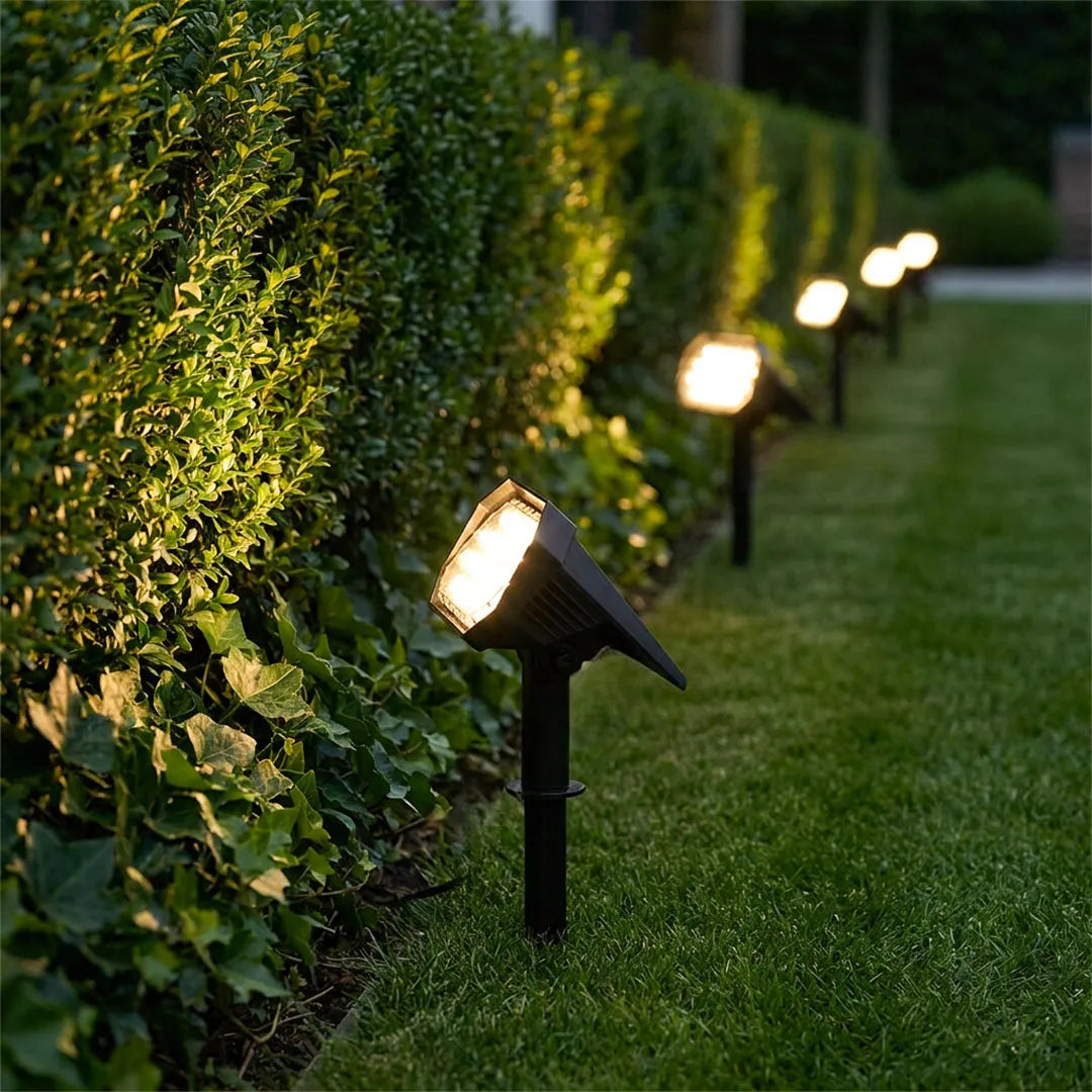 Garden stake solar lights arranged along a hedge to create focused outdoor pathway illumination.