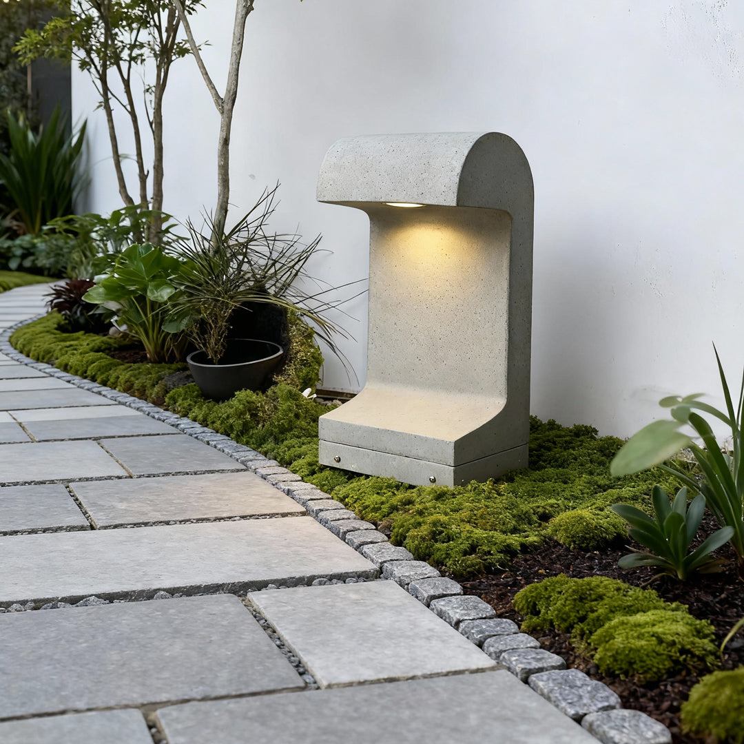 Soft landscape led lighting highlighting a garden walkway with a compact bollard fixture installed near a white exterior wall.