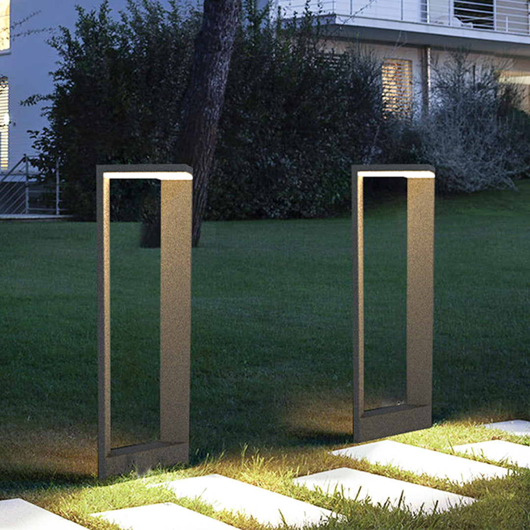 Tall square bollard light installed along a garden walkway providing soft outdoor illumination.