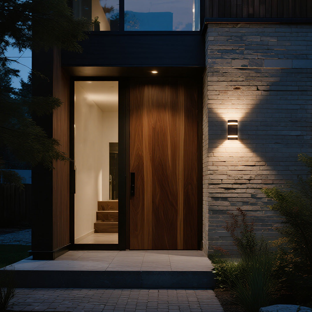 Garden wall light illuminating contemporary entrance with stone cladding and glass door
