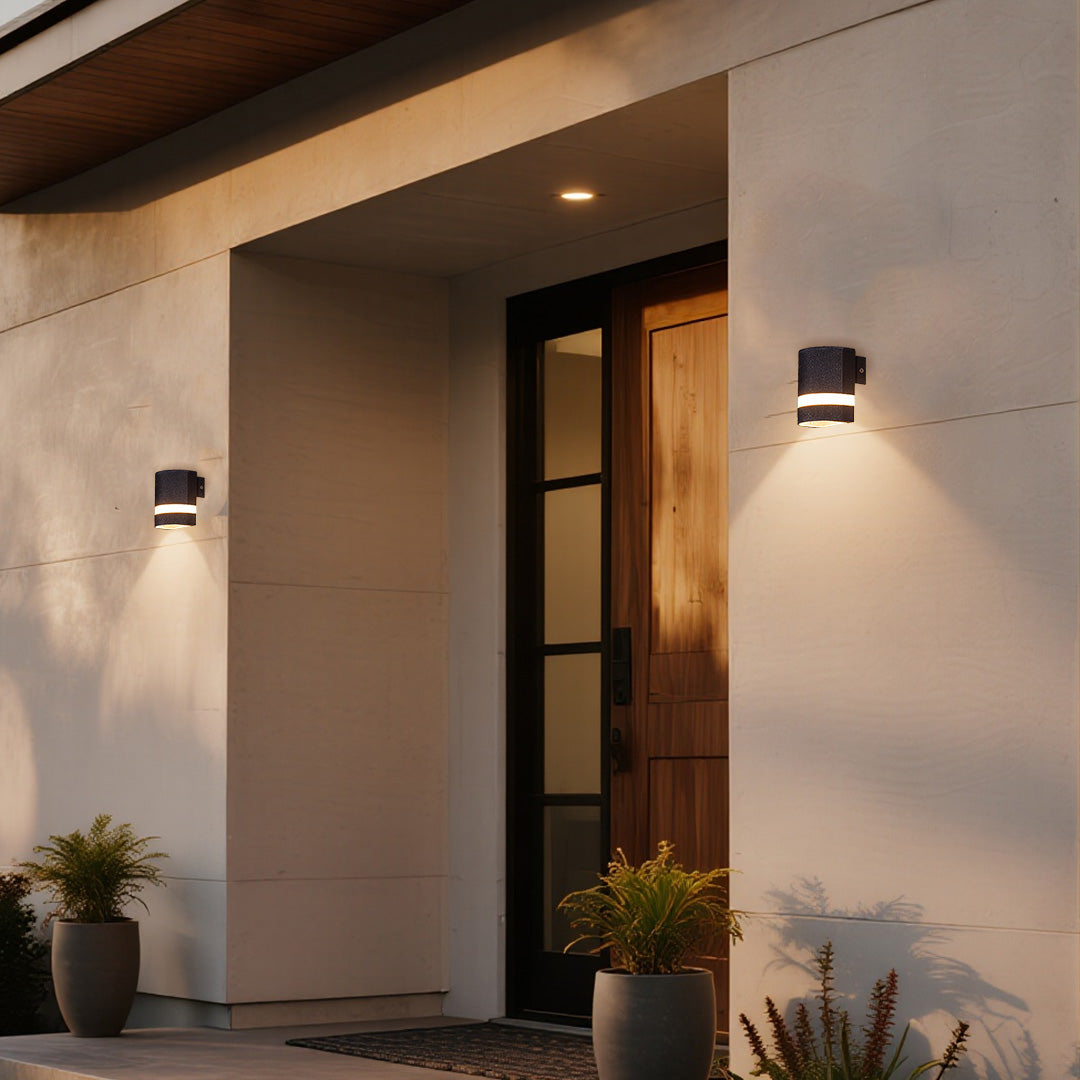 Garden wall light casting warm beam on neutral wall next to wooden door at evening