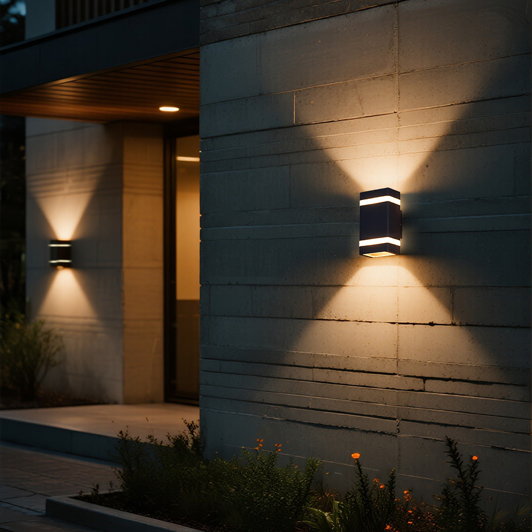 Garden wall lights creating ambient lighting on modern dark exterior wall at dusk