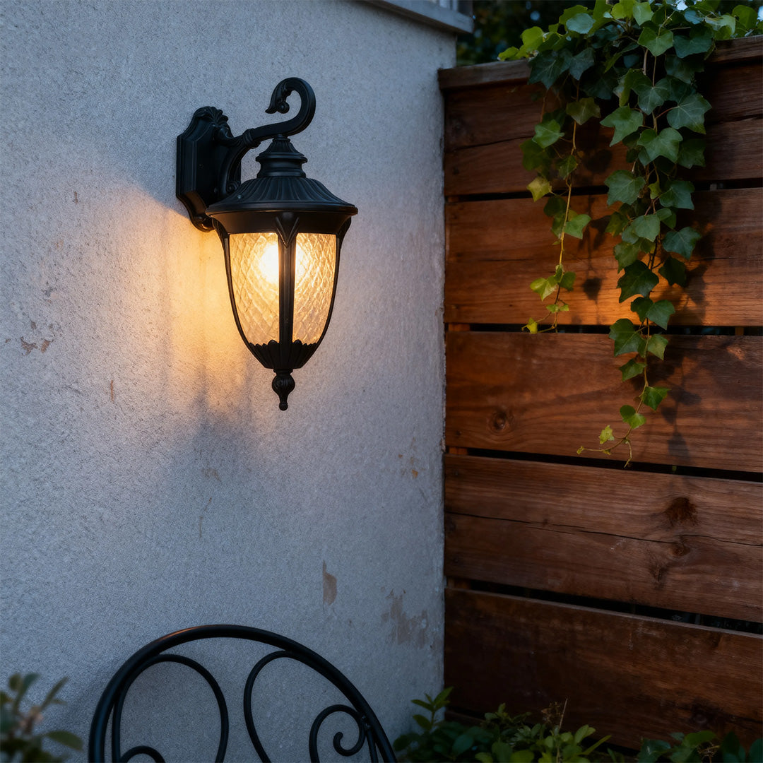Outdoor black wall sconce illuminating a garden wall, warm and inviting exterior lighting