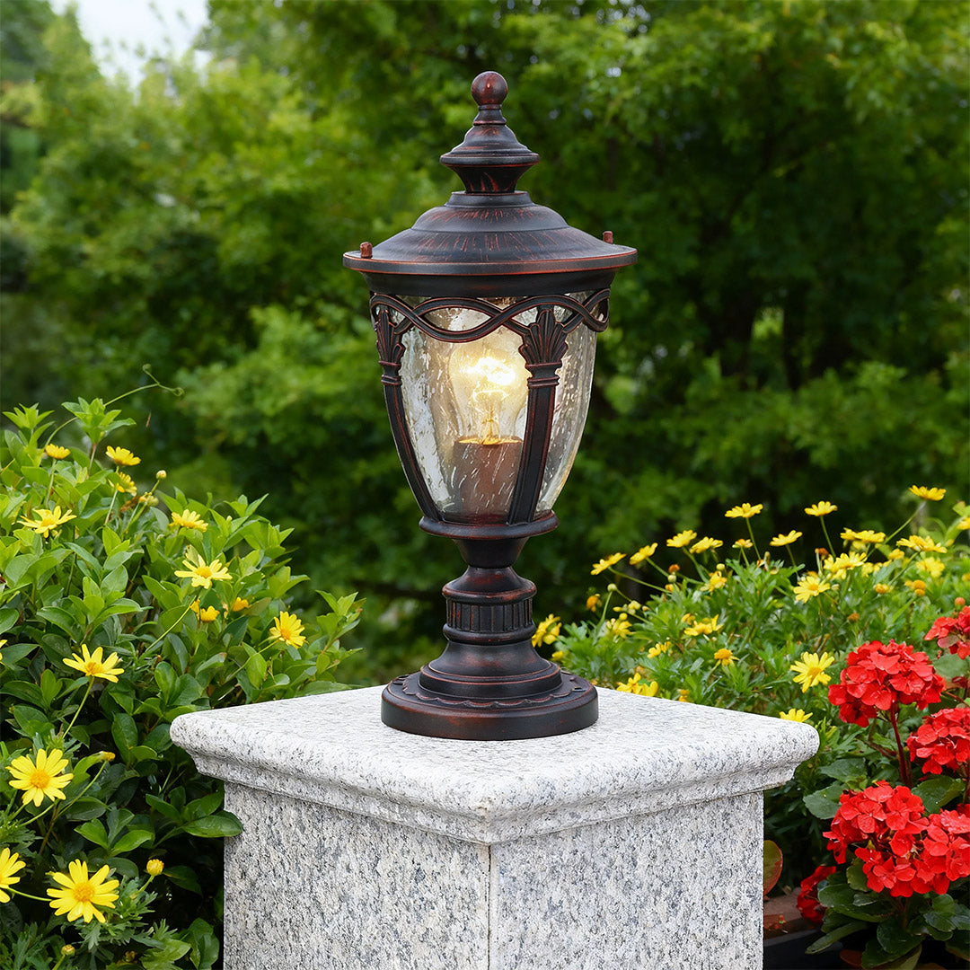 Gate pillar light brightening grey granite column in landscaped garden with red flowers and greenery