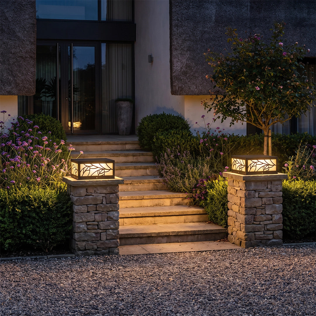 Gate pillar lights installed on stone columns beside front steps, casting warm outdoor light.