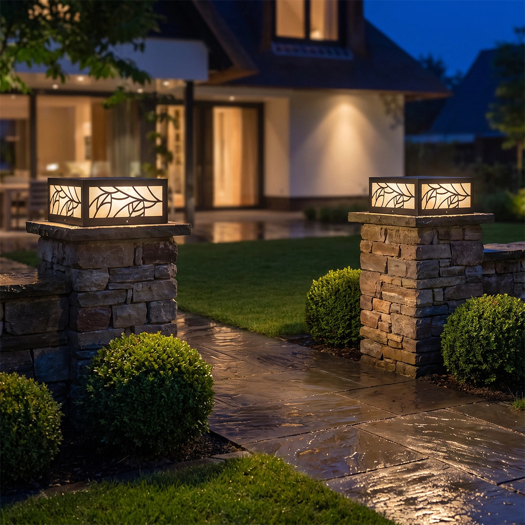 Gate pillar lights mounted on stone columns, lighting a garden entry path at night.