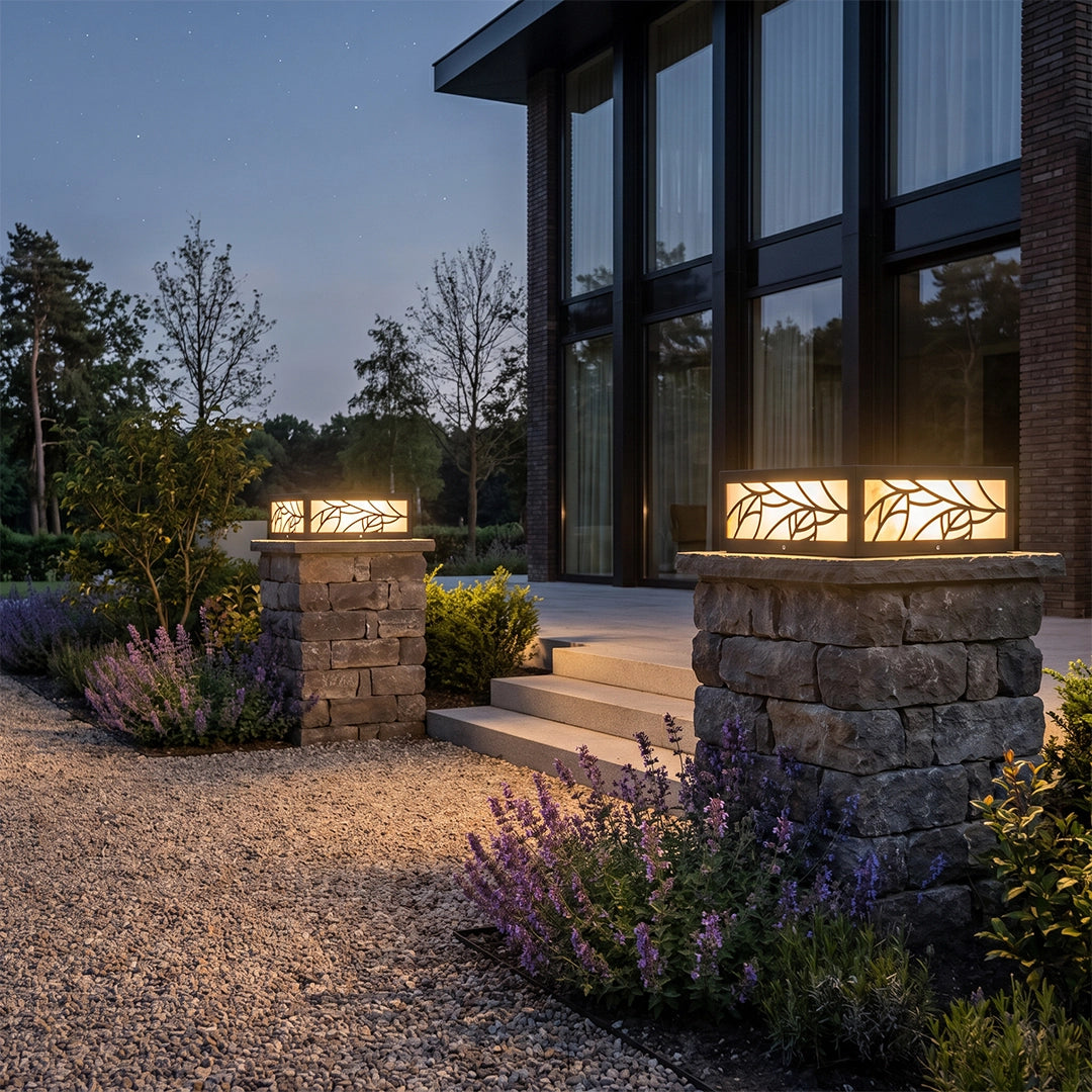 Gate pillar lights glowing on stone columns beside a gravel path and modern home entry.