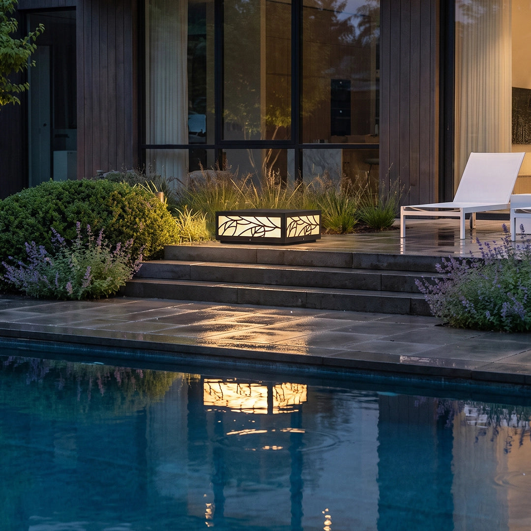 Gate pillar lights illuminating poolside steps and reflecting softly on the water at dusk.