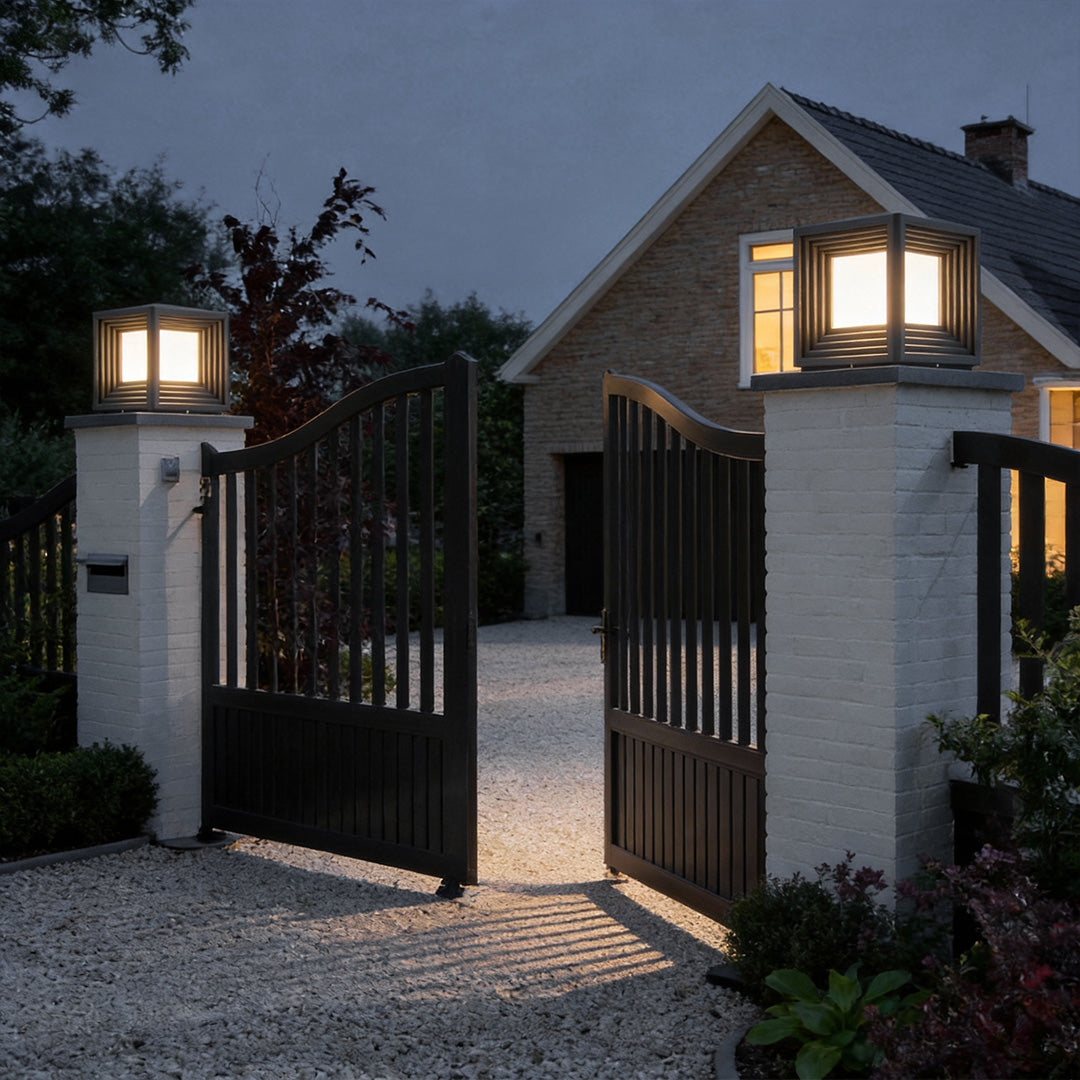 Sleek gate pillar lights mounted on brick pillars, lighting up a driveway at night.