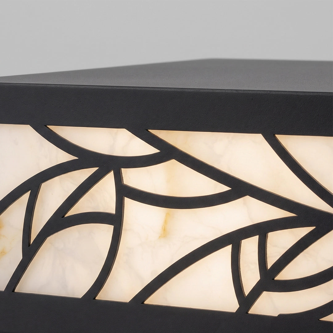 Close-up of a gate pillar light with a black top and decorative leaf-patterned panel.
