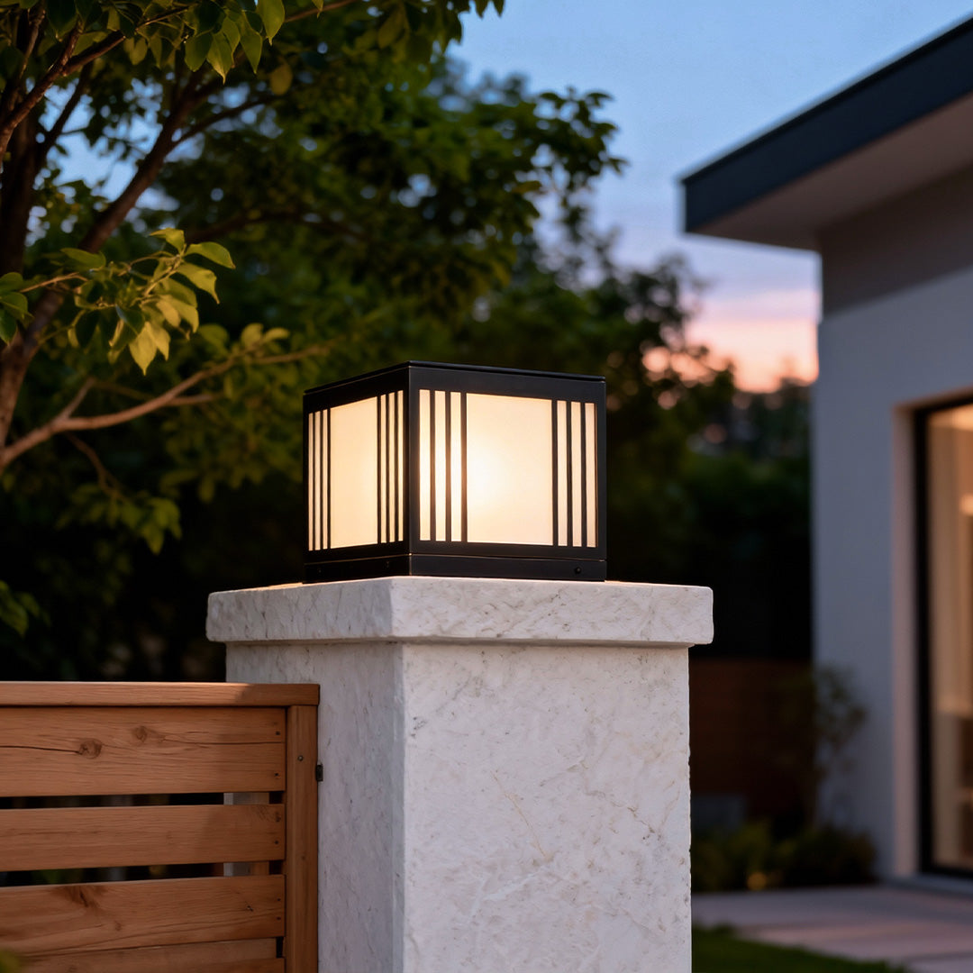 Gate pillar solar light illuminating a garden pathway beside a wooden fence at dusk.