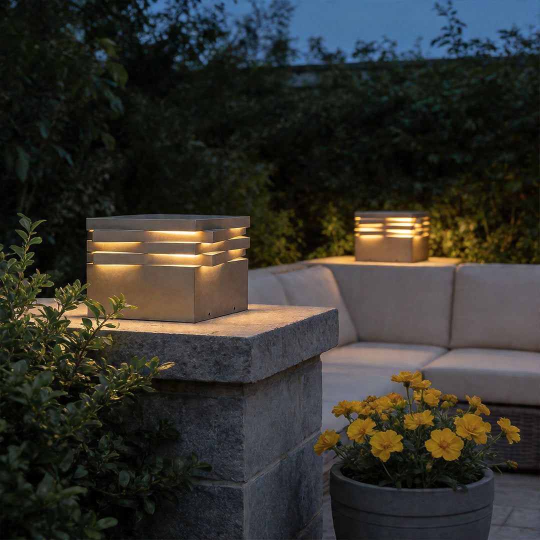 Gate post solar pillar light beside outdoor seating area providing warm ambient landscape lighting.