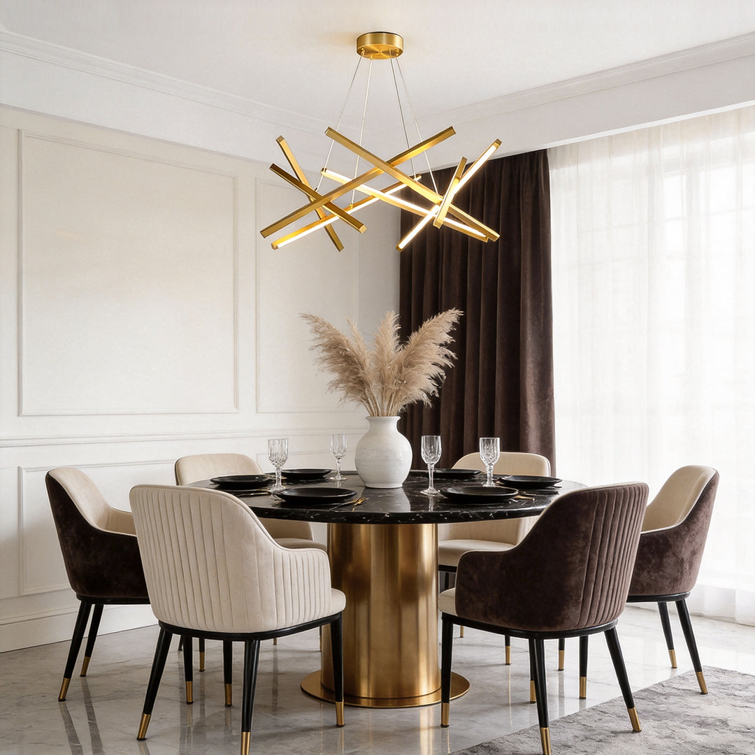 Geometric ceiling light featuring intersecting gold LED rods above a contemporary dining table, adding sculptural style and elegant illumination.