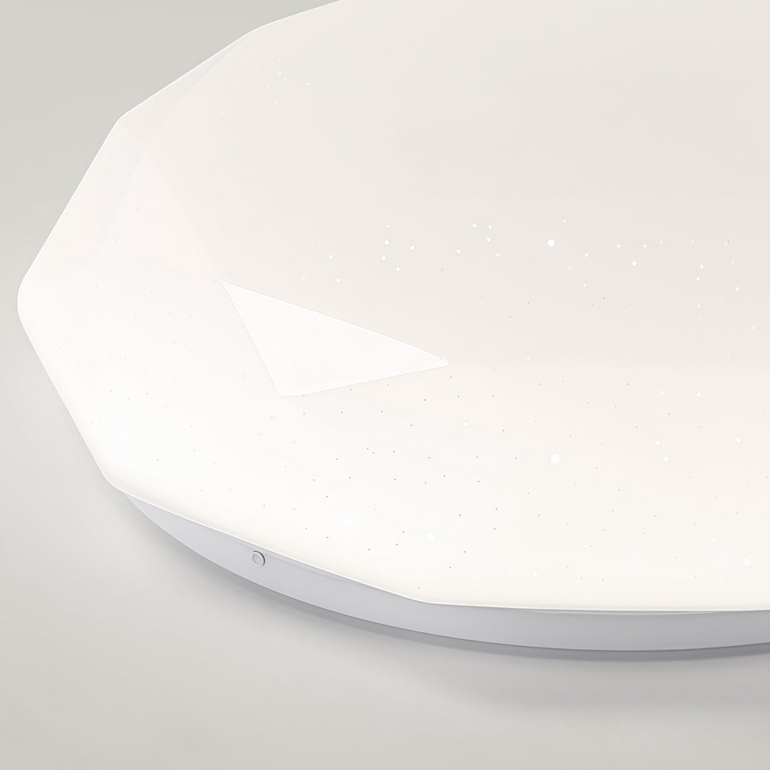 Close-up view of a geometric flush mount ceiling light with diamond-cut acrylic shade and subtle sparkle.