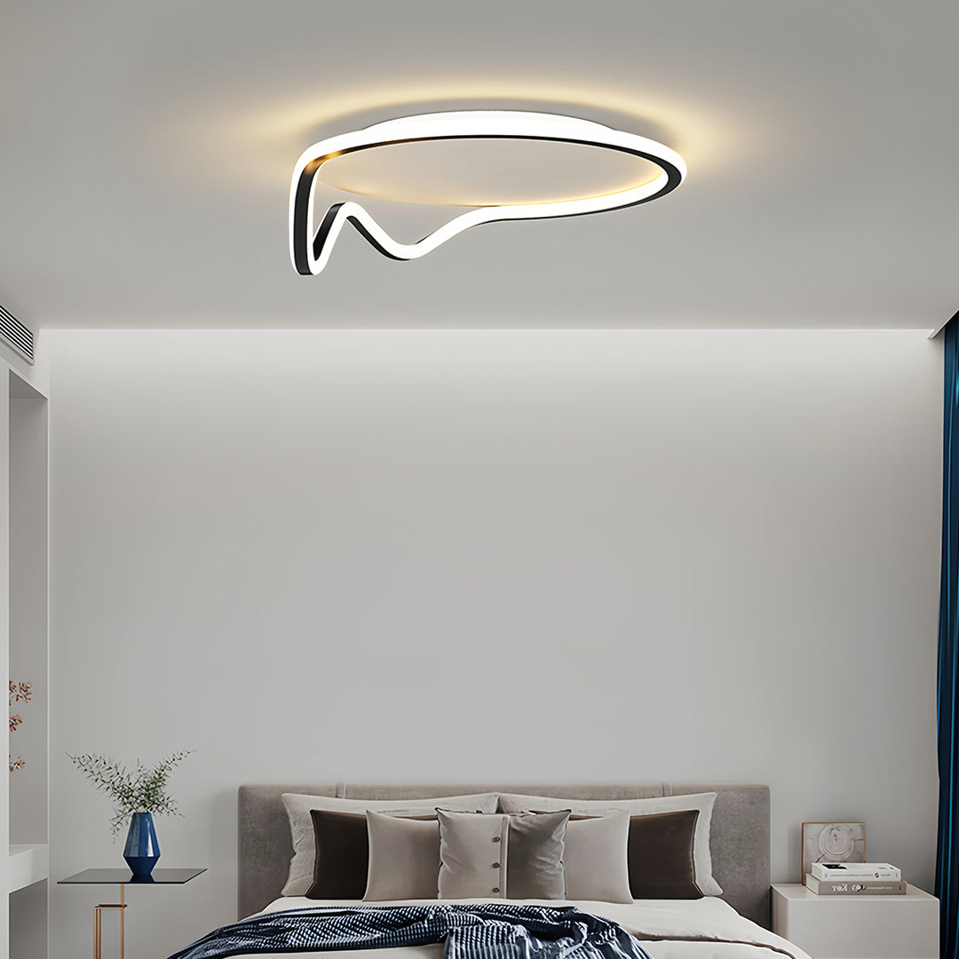 Geometric flush mount light with contrasting black and white lines, mounted on a ceiling above a large bed for ambient lighting.