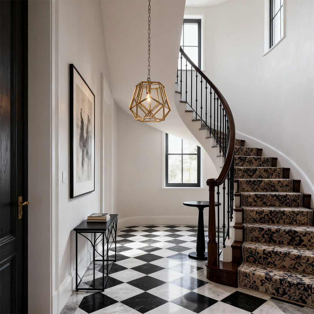 Geometric gold hanging pendant light illuminating a grand foyer with a black and white checkerboard floor and spiral staircase.