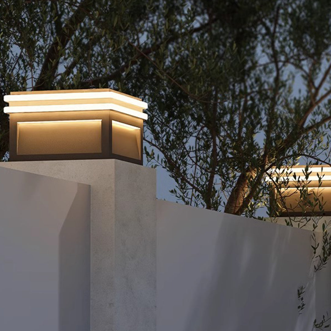 Sleek metal pillar lights with integrated warm lighting strips mounted on geometric concrete structures for landscape illumination