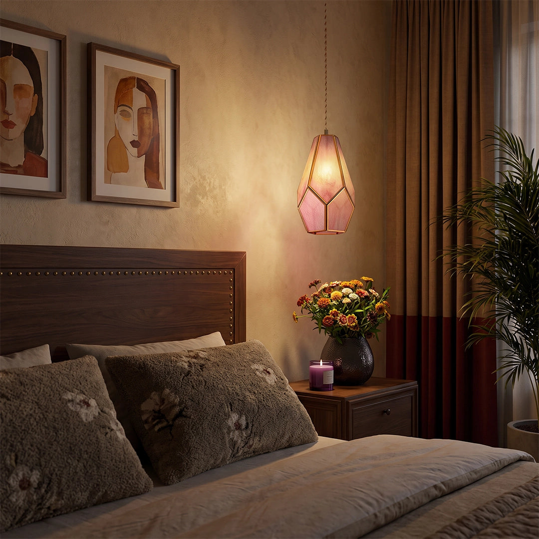 Geometric pendant light glowing beside a bed in a cozy bedroom with framed wall art.