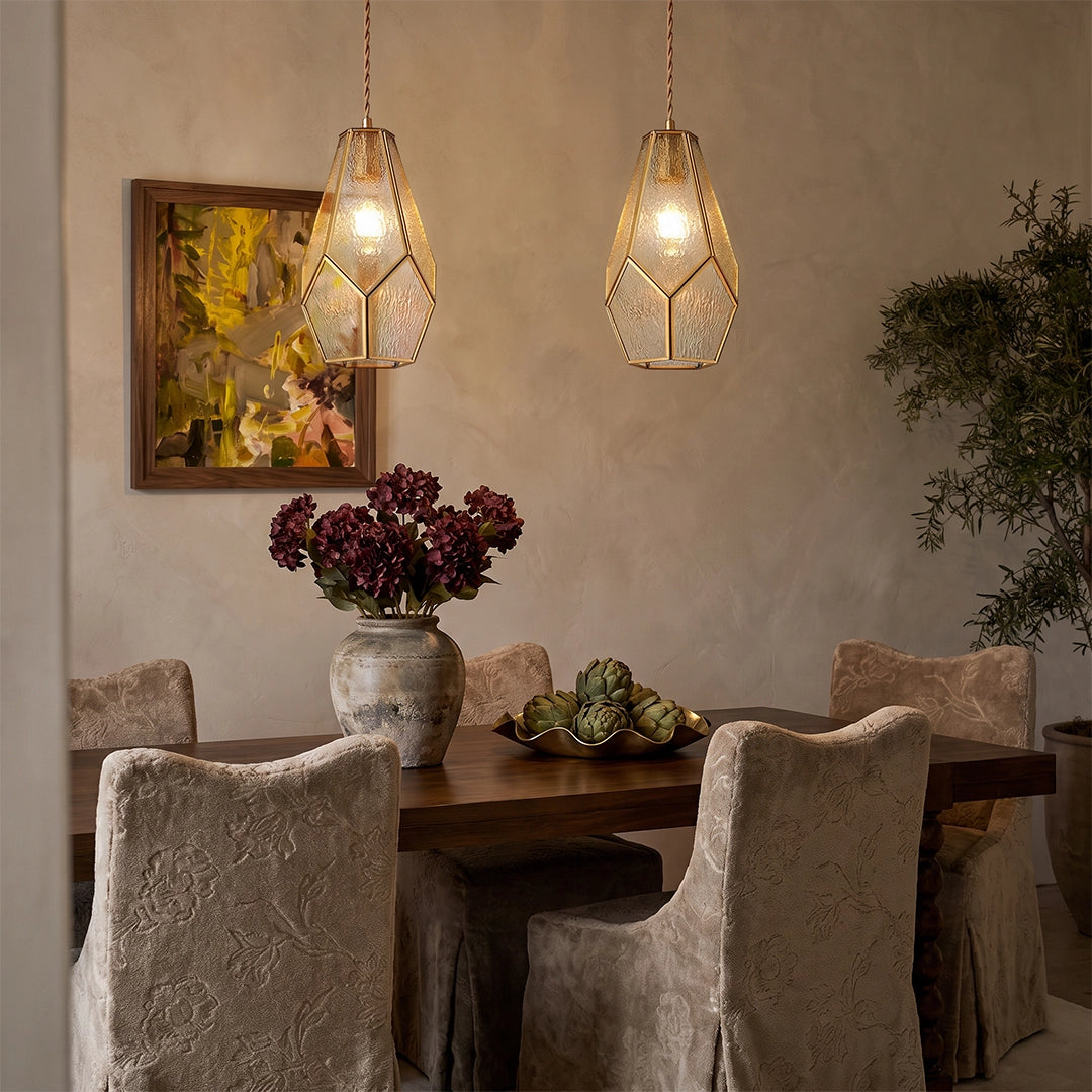 Geometric pendant light hanging above a dining table in a warm, textured dining room.