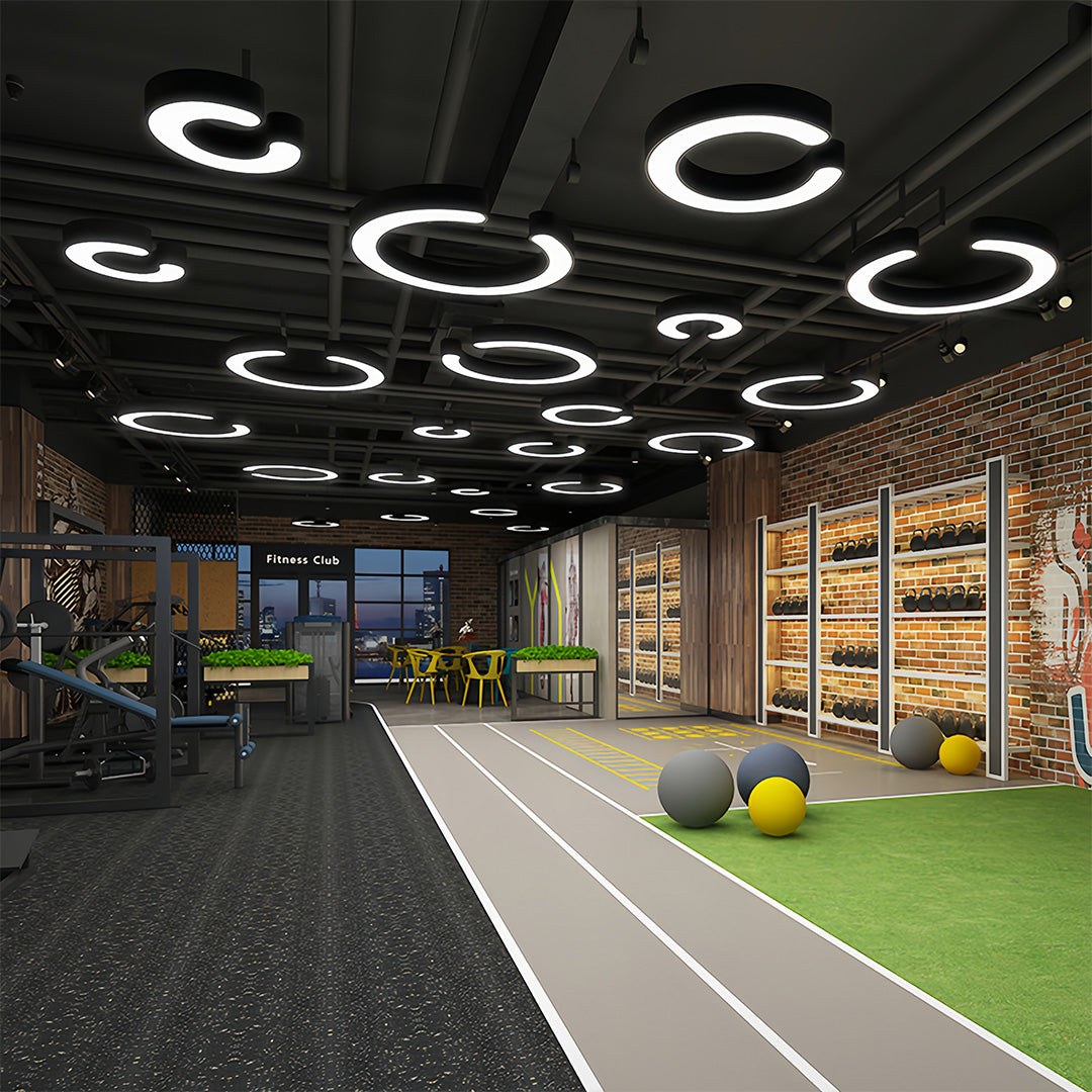 Array of geometric pendant lights suspended above open workspace with grass turf flooring