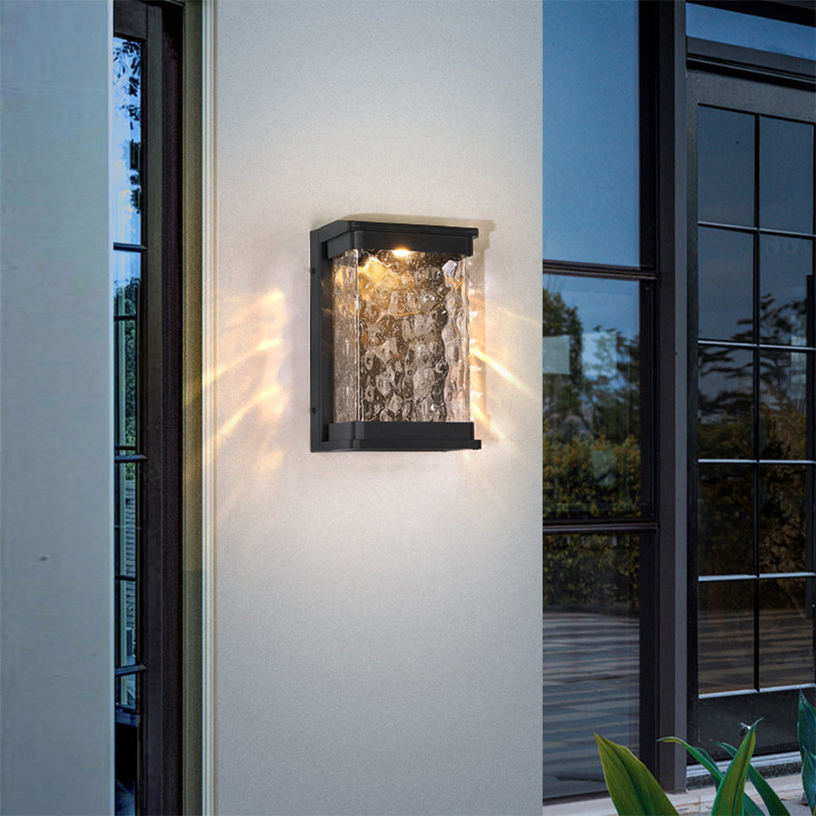 Geometric wall sconce with decorative glass pattern providing accent lighting on building exterior